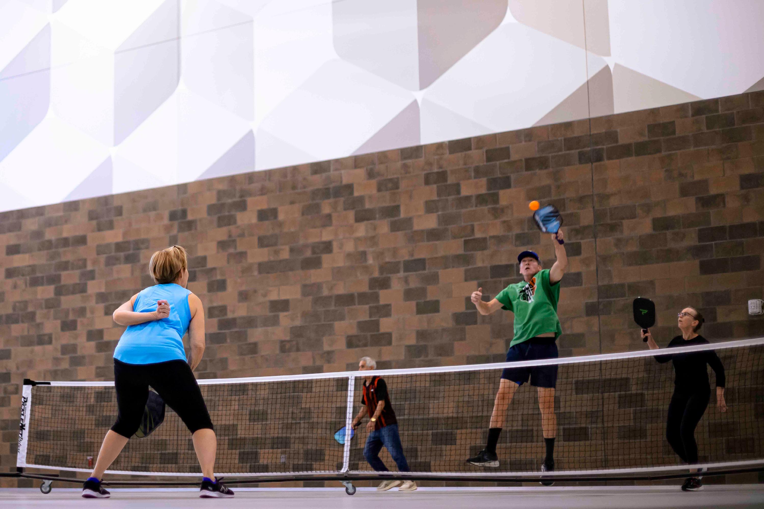 Three adults play pickleball at the Maryland Heights Community Center